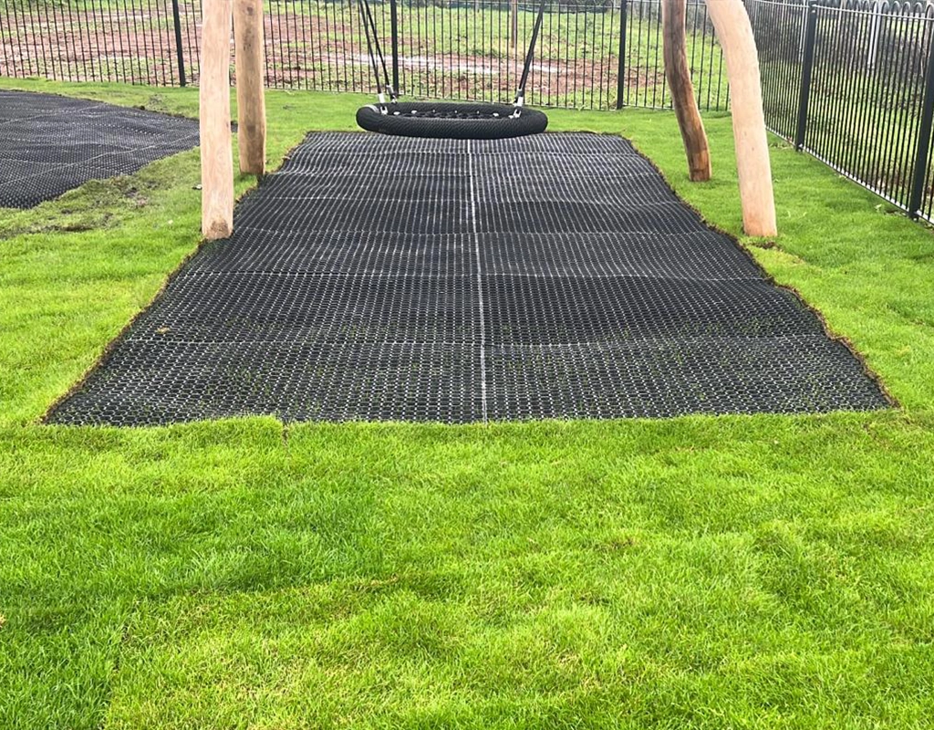 visible Ecosmart mat to protect grass under wooden playground equipment