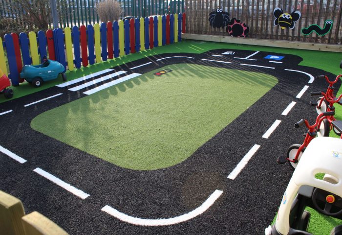 Artificial Grass Carpet | Race Track Green Frog Artificial Grass used in a rectangular road track on a play area, with green artificial grass at the centre and black and white patterned artificial grass used for the road design.